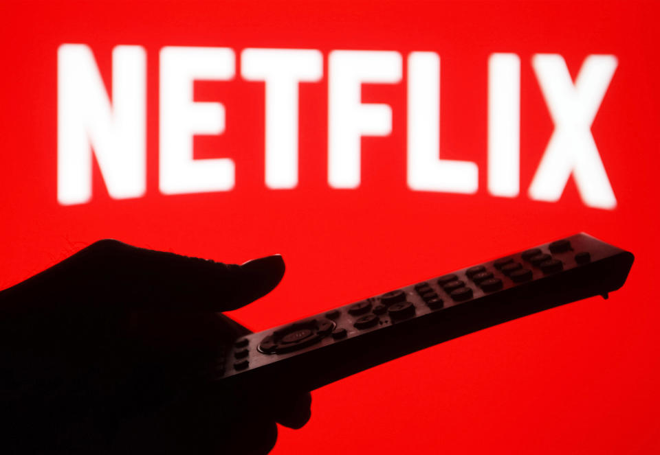 UKRAINE - 2021/01/20: In this photo illustration a silhouette of a hand holding a TV remote seen displayed in front of the Netflix logo. (Photo Illustration by Pavlo Gonchar/SOPA Images/LightRocket via Getty Images)
