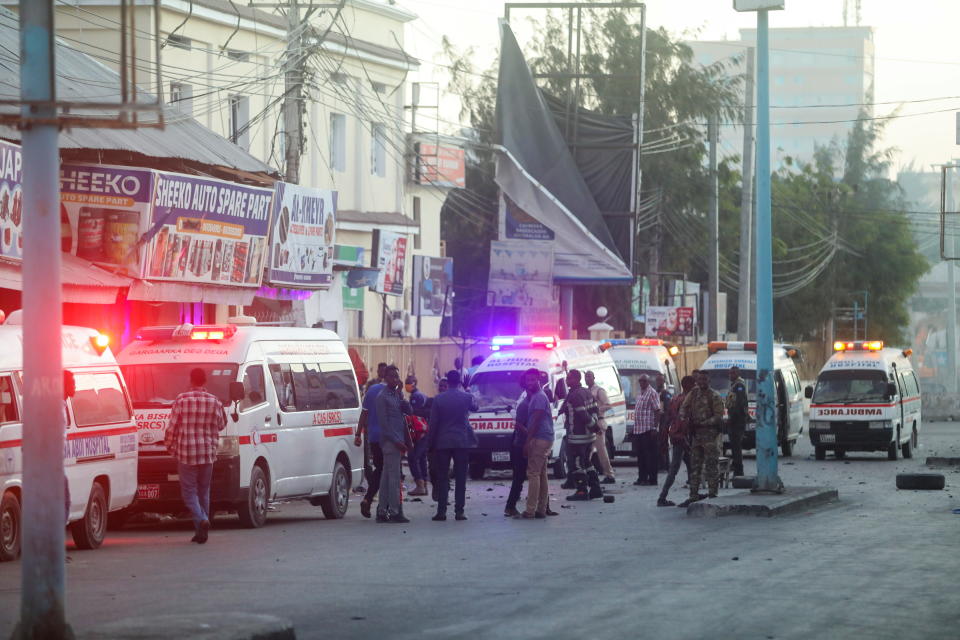 Somali security officers secure the site of a car bomb explosion as paramedics await to rescue the injured in the Kilometre 4 area of Mogadishu, Somalia.