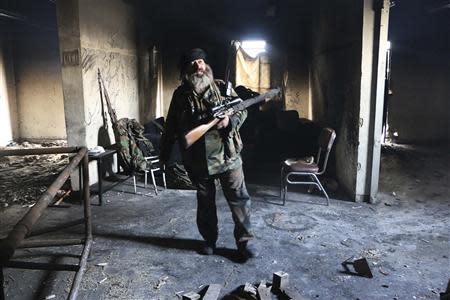 A Free Syrian Army fighter stands with his weapon inside a damaged building in Aleppo's Sheikh Maqsoud neighbourhood, February 16, 2014. REUTERS/Hosam Katan