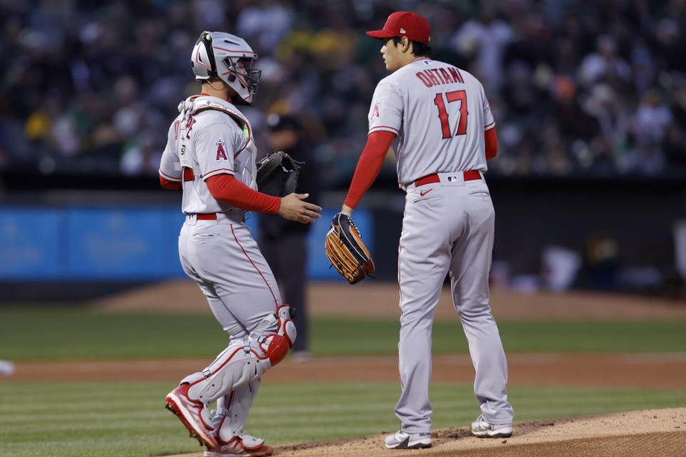 Angels pitcher Shohei Ohtani speaks with catcher Logan O'Hoppe on the field.