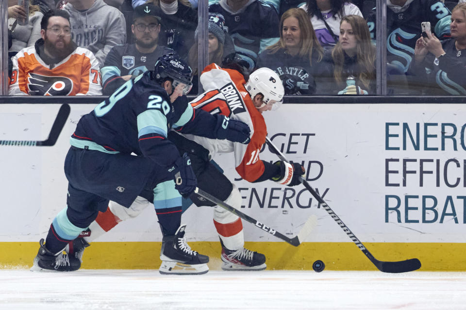 Seattle Kraken defenseman Vince Dunn, left, and Philadelphia Flyers right wing Bobby Brink (10) battle for the puck during the first period of an NHL hockey game, Friday, Dec. 29, 2023, in Seattle. (AP Photo/John Froschauer)