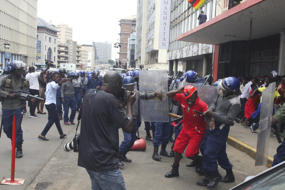 Police surround opposition party supporters who had gathered to hear a speech by the country's top opposition leader in Harare, Wednesday, Nov. 20, 2019. Zimbabwean police with riot gear fired tear gas and struck people who had gathered at the opposition party headquarters to hear a speech by the main opposition leader Nelson Chamisa who still disputes his narrow loss to Zimbabwean President Emmerson Mnangagwa. (AP Photo/Tsvangirayi Mukwazhi)
