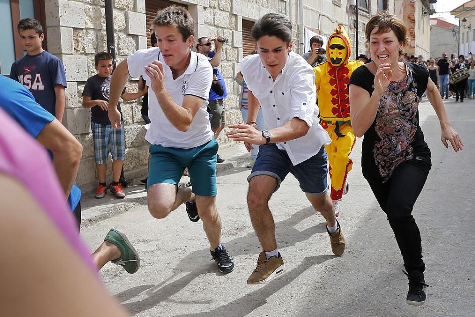 A man dressed up as the devil chases children during 'El Colacho', the 'baby jumping festival' on June 22, 2014 in the village of Castrillo de Murcia, near Burgos. Baby jumping (El Colacho) is a traditional Spanish practice dating back to 1620 that takes place annually to celebrate the Catholic feast of Corpus Christi. During the act - known as El Salto del Colacho (the devil's jump) or simply El Colacho - men dressed as the Devil jump over babies born in the last twelve months of the year who lie on mattresses in the street. AFP PHOTO / CESAR MANSO