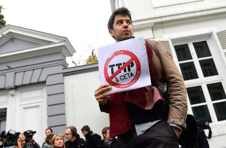 A demonstrator holds a poster reading 'Stop TTIP - Stop CETA' ahead of an emergency meeting of all Belgium federal entities on the EU-Canada Comprehensive Economic and Trade Agreement (CETA) in Brussels on October 24, 2016