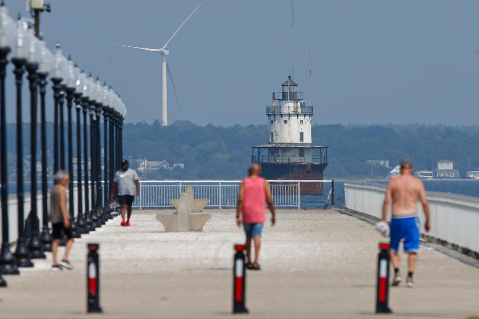 People walk toward the Butler Flats lighthouse in the distance on the pier at Fort Taber Park in New Bedford Thursday. City beaches, CoveWalk, HarborWalk, and Fort Taber will be closed to the public, effective Friday, Sept. 15, at 8 p.m.