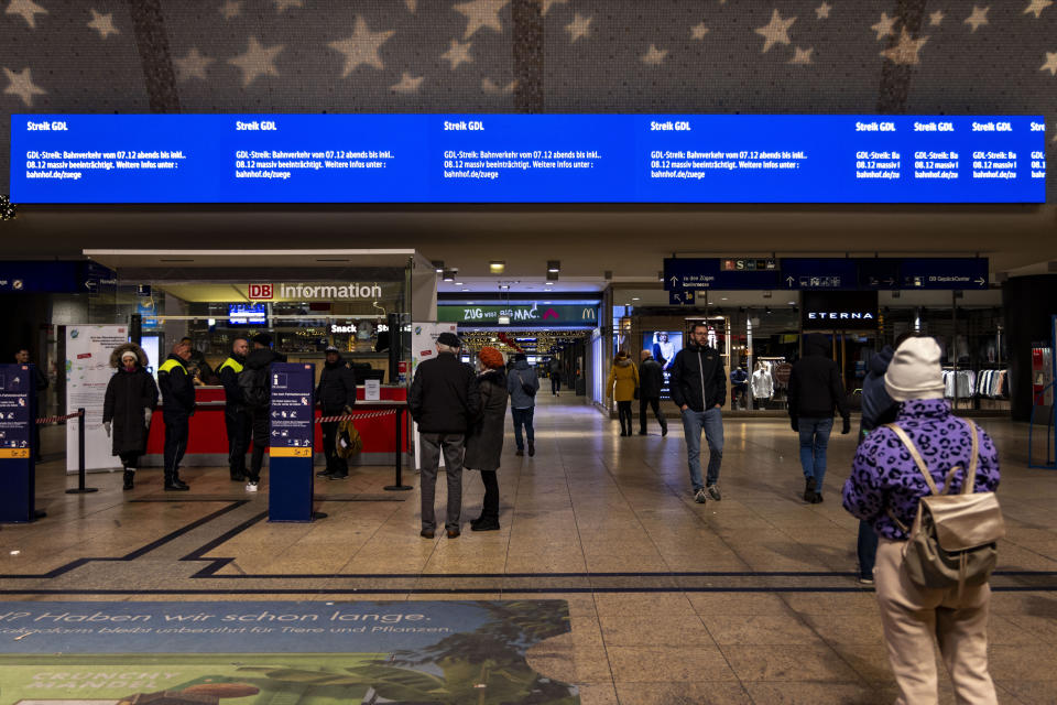 Travelers get information at the DB information desk; a screen above informs travelers about the strike in Cologne, Germany, Thursday, Dec. 7, 2023. The GDL union said the strike will affect passenger services operated by state-owned Deutsche Bahn from 10 p.m. on Thursday until 10 p.m. on Friday. Freight trains will be hit from 6 p.m. Thursday. (Christoph Reichwein/dpa via AP)