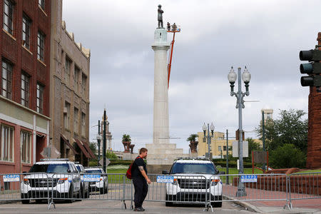 A man crosses the street as a construction crew prepares a monument of Robert E. Lee, who was a general in the Confederate Army, for removal in New Orleans, Louisiana, U.S., May 19, 2017. REUTERS/Jonathan Bachman