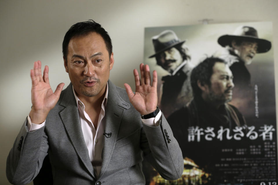 In this Tuesday, Sept. 3, 2013 photo, Japanese actor Ken Watanabe getsures during an interview in Tokyo. The Japanese remake of Clint Eastwood’s “Unforgiven” isn’t a mere cross-cultural adaptation but more a tribute to the universal spirit of great filmmaking for its star Watanabe. “I was convinced from the start that this will be an original Japanese movie in its own right,” said Watanabe, who has become the go-to Japanese actor for Hollywood. Watanabe was happy Eastwood welcomed the idea of the remake, and they kept in touch. But, once the shooting began, he was focused on delivering what director Lee Sang-il wanted in the new movie, not an easy re-interpretation. Japanese characters written on the poster reads: "Unforgiven." (AP Photo/Shizuo Kambayashi)