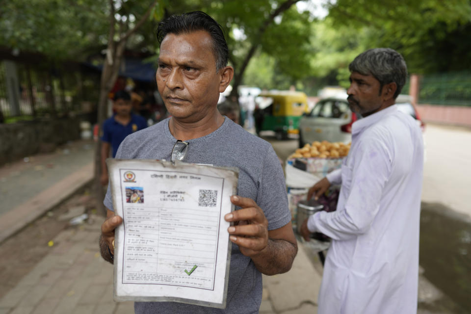 Roadside vendor Shankar Lal shows his government permit to run a stall in New Delhi, India, Thursday, Aug. 24, 2023. Shankar Lal said he hasn't opened his stall, where he sells chickpea curry with fried flatbreads, for three months after authorities told him to move away. "The government doesn't know whether we are dying of hunger or not," Lal said. (AP Photo/Manish Swarup)