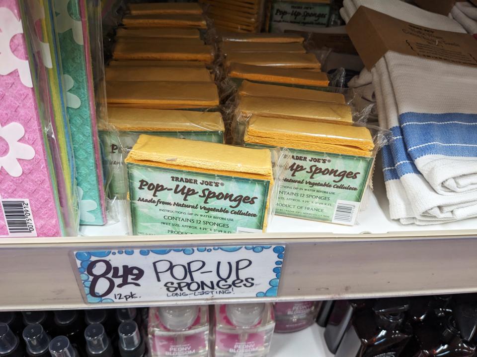 Yellow Pop-up Sponges on a shelf next to towels at Trader Joe's.