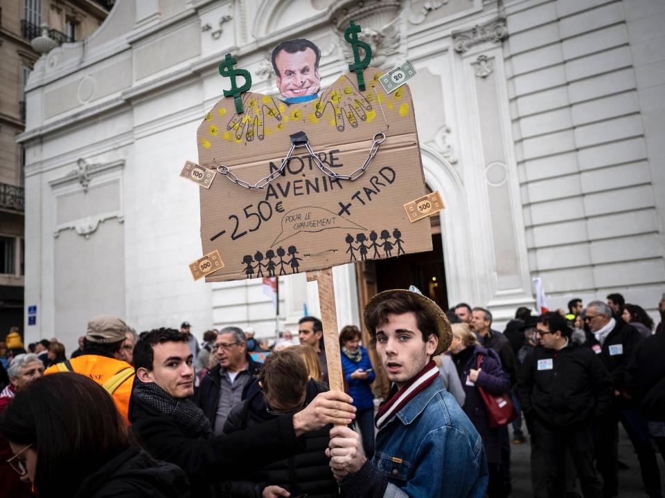 A protester holds up a sign as public and private workers demonstrate and shout slogans during a mass strike against pension reforms on December 05, 2019 in Marseille, France.