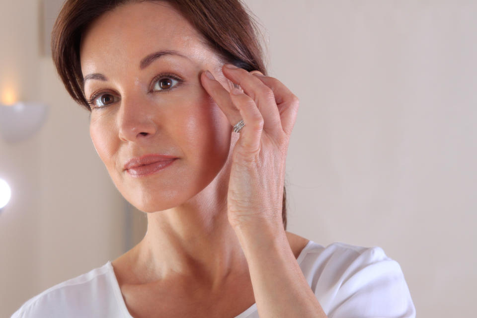 Photo of a brunette-haired woman touching her face