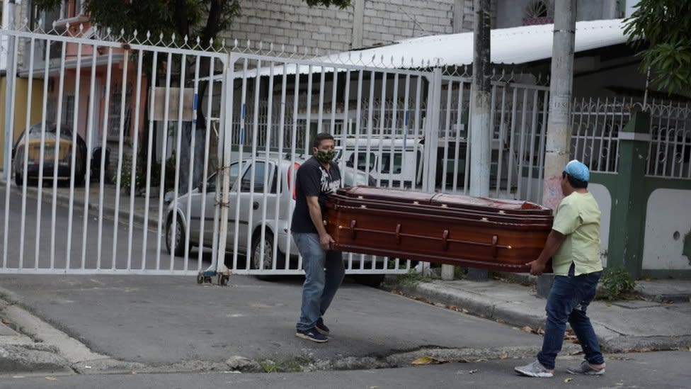 Dos hombres llevan un ataúd por las calles de Guayaquil.