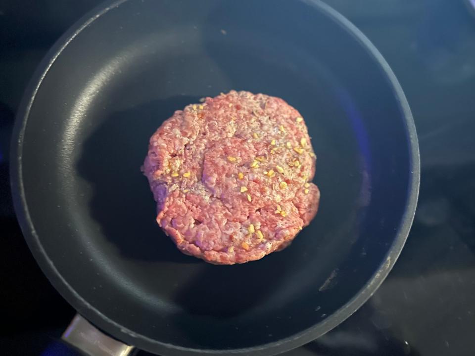raw burger patty in a pan on the stove