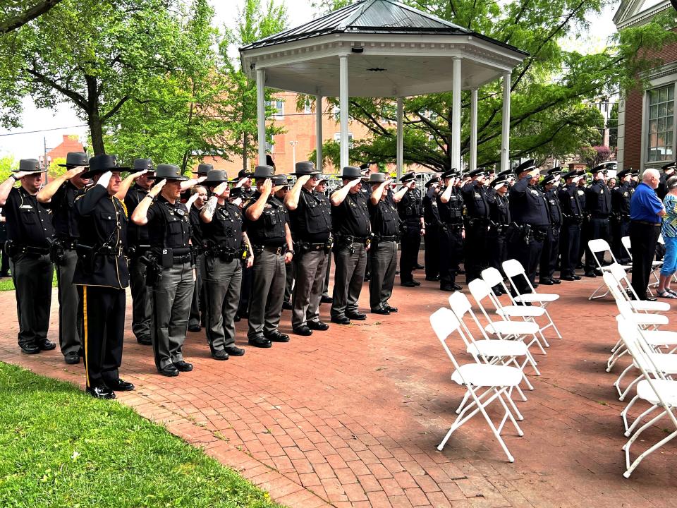Local law enforcement officers salute during the National Anthem at Friday's annual police memorial ceremony near the downtown bandstand at Main and Broad streets.