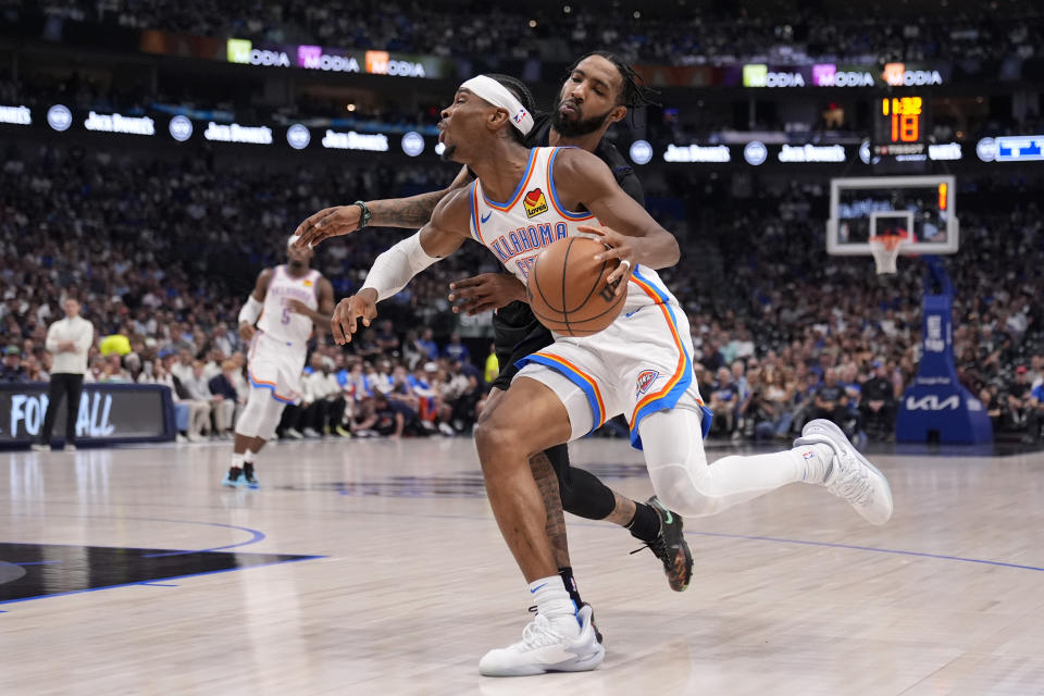 Oklahoma City Thunder guard Shai Gilgeous-Alexander is fouled drivig to the basket by Dallas Mavericks' Derrick Jones Jr., rear, in the first half of Game 6 of an NBA basketball second-round playoff series Saturday, May 18, 2024, in Dallas. (AP Photo/Tony Gutierrez)