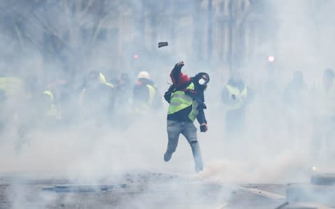  A protestor wearing a "yellow vest" (Gilet jaune) throws a cobble at police forces - Credit: THOMAS SAMSON/AFP/Getty Images