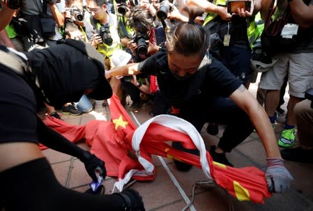 An anti-government protester destroys a Chinese flag during a protest in Tuen Mun, Hong Kong