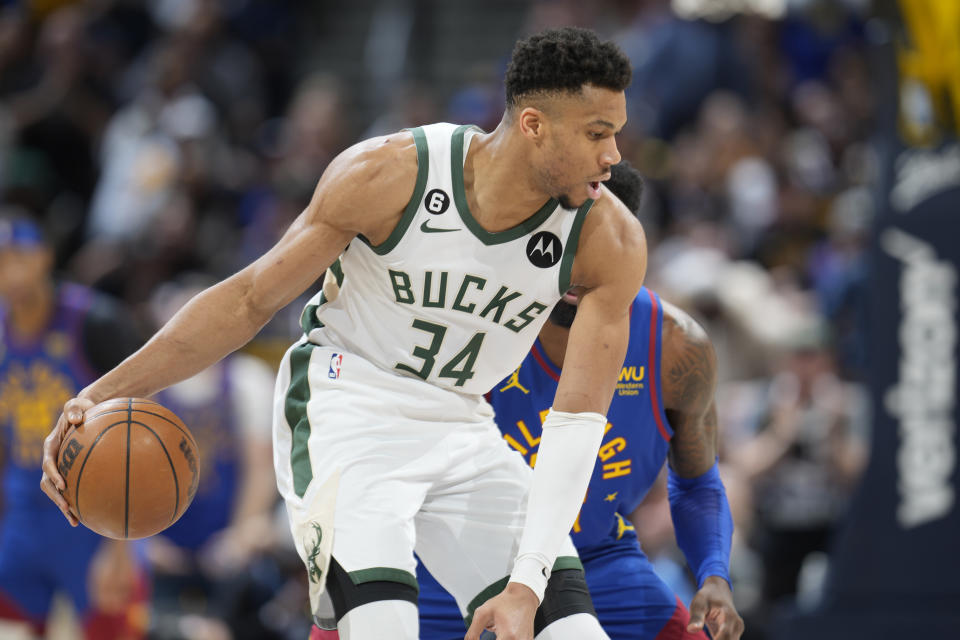 Milwaukee Bucks forward Giannis Antetokounmpo, front, looks to pass the ball as Denver Nuggets forward Jeff Green defends in the first half of an NBA basketball game Saturday, March 25, 2023, in Denver. (AP Photo/David Zalubowski)