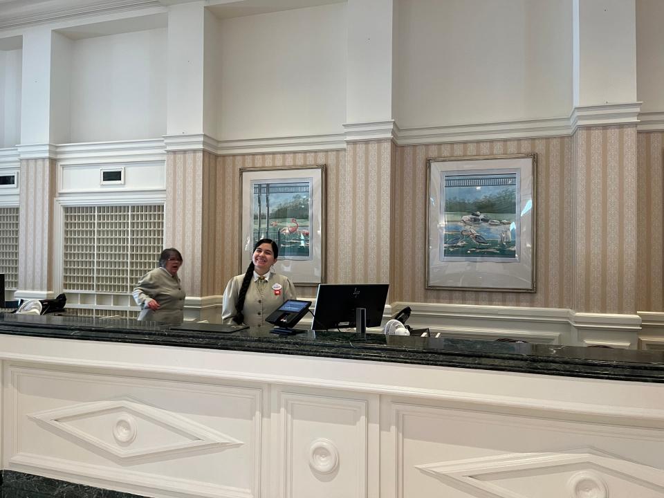 two disney grand floridian employees behind the check-in counter at the resort