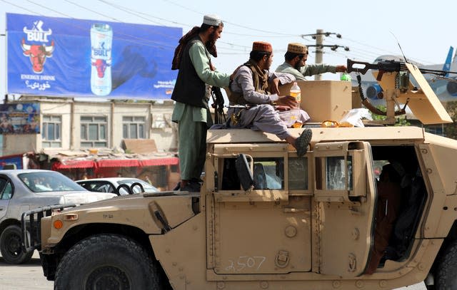 Taliban fighters stand guard in front of the Hamid Karzai International Airport, in Kabul, Afghanistan on Monday as thousands of people packed into the Afghan capital’s airport 