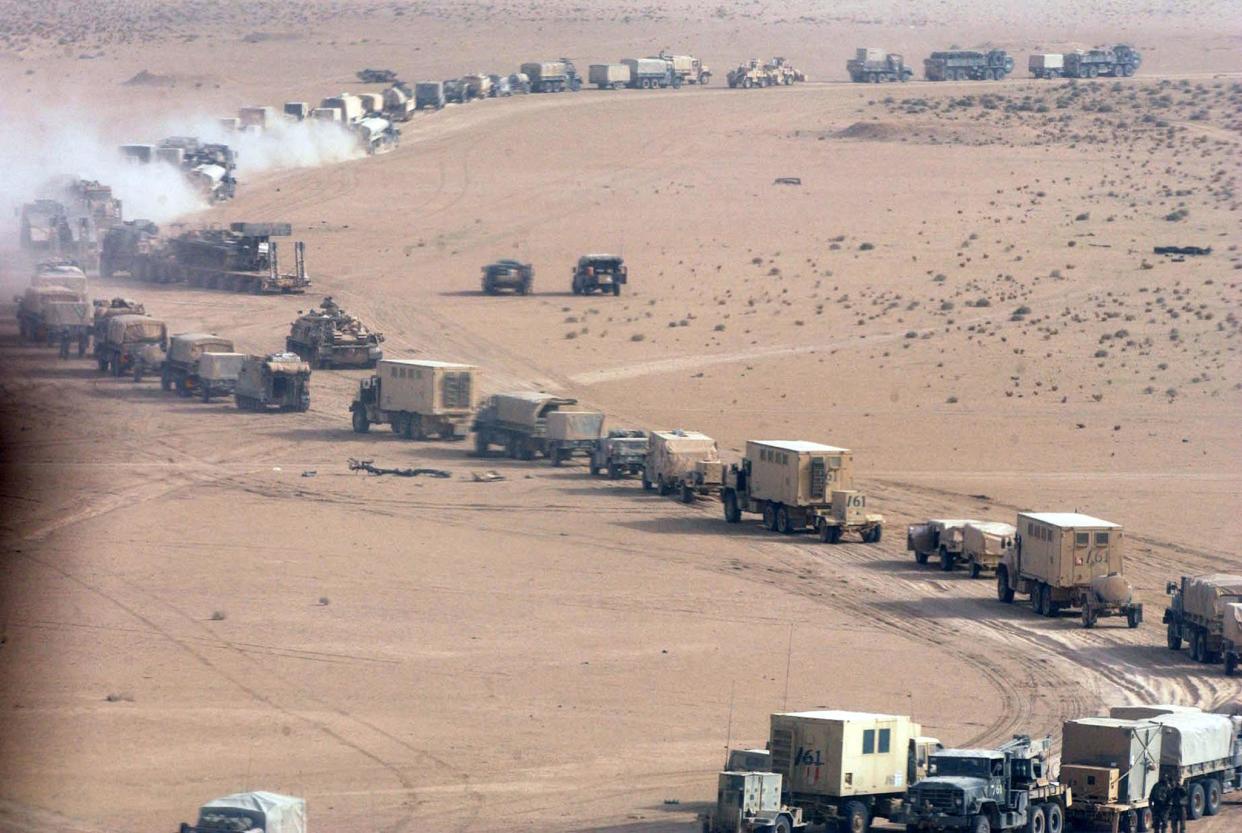 A U.S. military convoy of trucks and jeeps snakes through the desert.