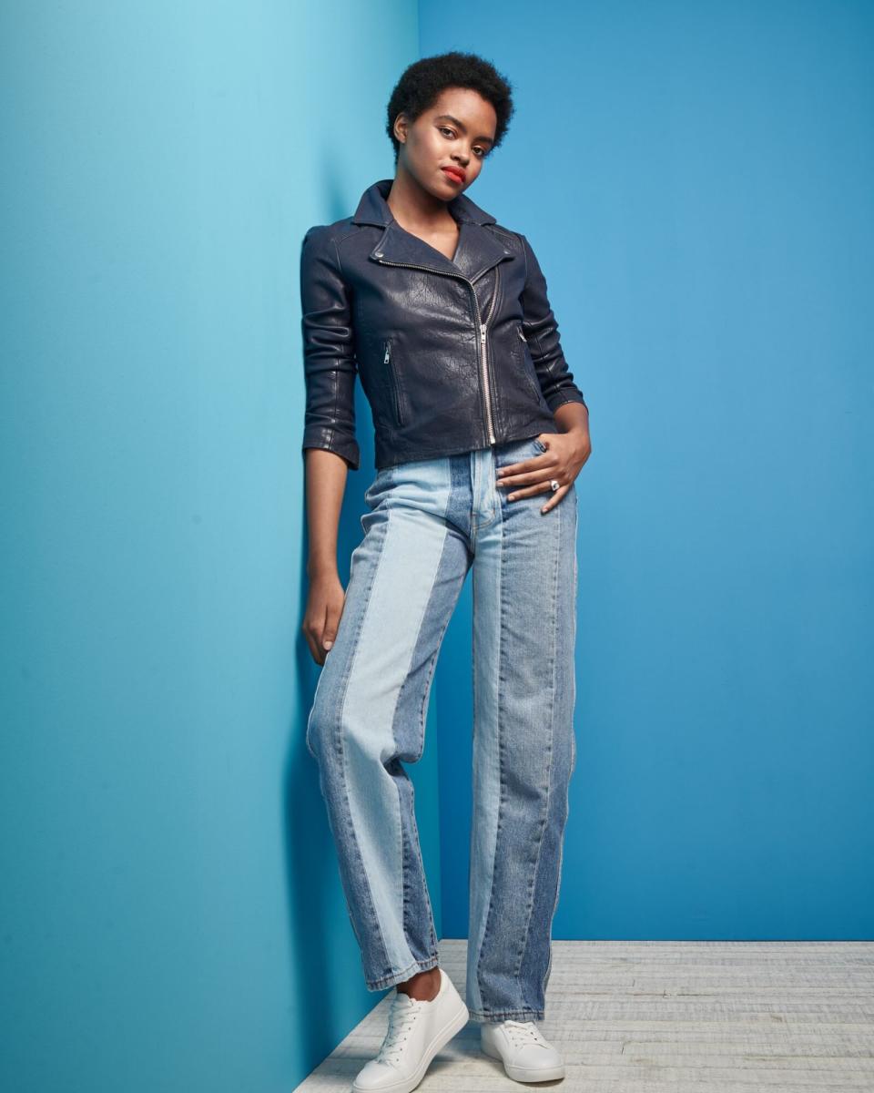 woman standing in blue room wearing denim