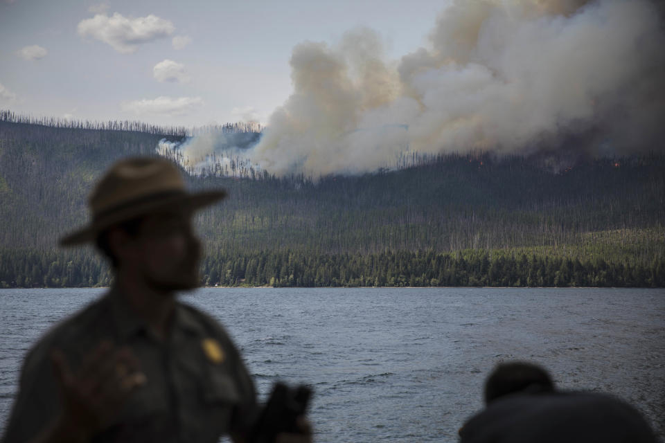 FILE - In this Sunday, Aug. 12, 2018 file photo provided by the National Park Service, an interpretive ranger talks to visitors about the Howe Ridge Fire from outside Lake McDonald Lodge in Glacier National Park, Mont. Wildfires burning in the U.S. this summer have upended plans for countless outdoor adventures. Campers, hikers, rafters and other outdoor enthusiasts have had to scrap or change plans or endure awful smoke. (National Park Service via AP,File)