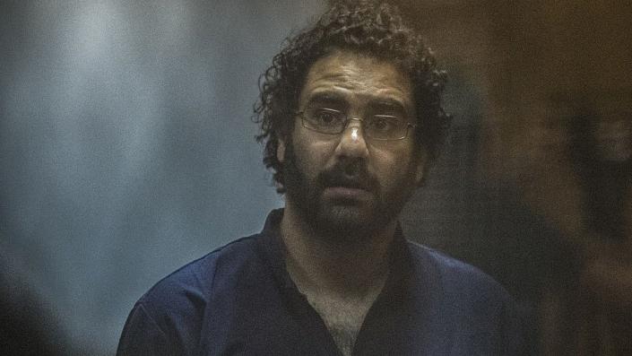 Egyptian activist and blogger Alaa Abdel Fattah looks on from behind the defendant's box during his trial for insulting the judiciary alongside 25 other defendants including ousted Egyptian president Mohamed Morsi, who was recently sentenced to death, in Cairo on May 23, 2015