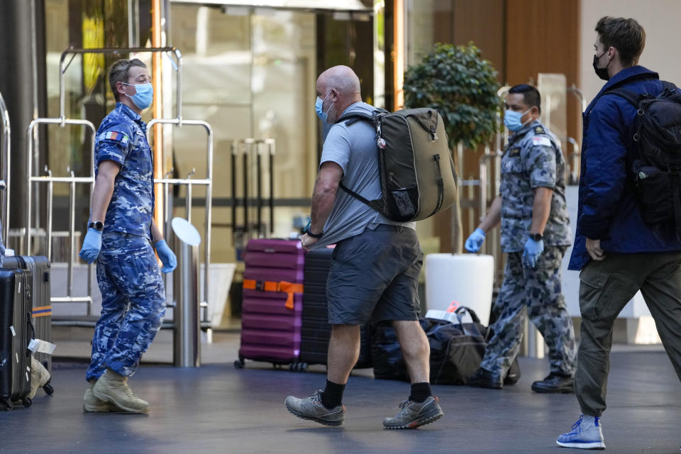 International travelers are met by Australian military personnel as they arrive at a quarantine hotel in Sydney, Australia on May 20, 2021. New South Wales state, which includes Sydney, has announced it will end hotel quarantine requirements for fully-vaccinated international travelers from Nov. 1, 2021 in a major relaxation in pandemic restrictions. (AP Photo/Mark Baker)