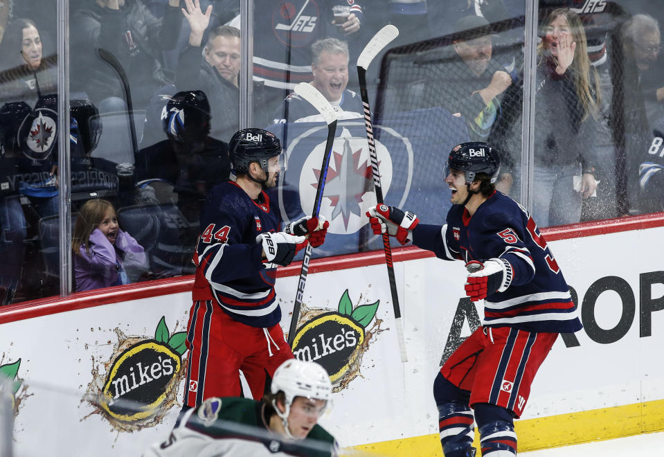 Winnipeg Jets' Josh Morrissey (44) and Mark Scheifele (55) celebrate Morrissey's goal against the Arizona Coyotes during the third period of an NHL hockey game, Saturday, Nov. 18, 2023 in Winnipeg, Manitoba. (John Woods/The Canadian Press via AP)