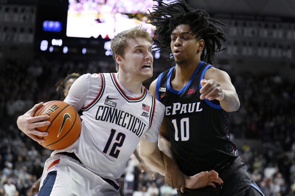 UConn guard Cam Spencer (12) drives to the basket as DePaul guard Jaden Henley (10) defends in the first half of an NCAA college basketball game, Tuesday, Jan. 2, 2024, in Storrs, Conn. (AP Photo/Jessica Hill)