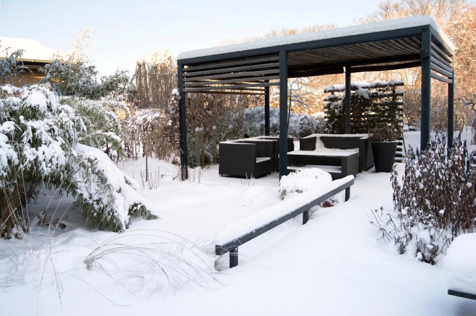 Sleek and modern pergola covered in winter snow. 