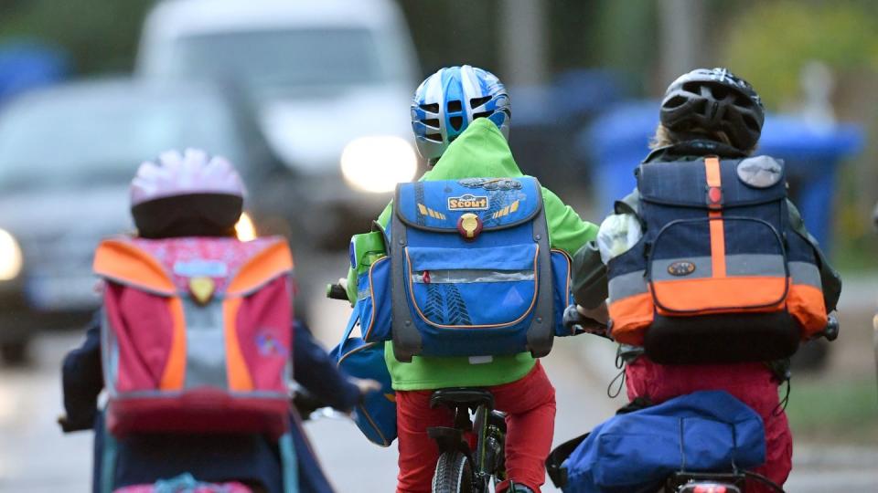 Kinder sind auf einer Straße mit dem Fahrrad unterwegs zur Schule. (Archivbild)