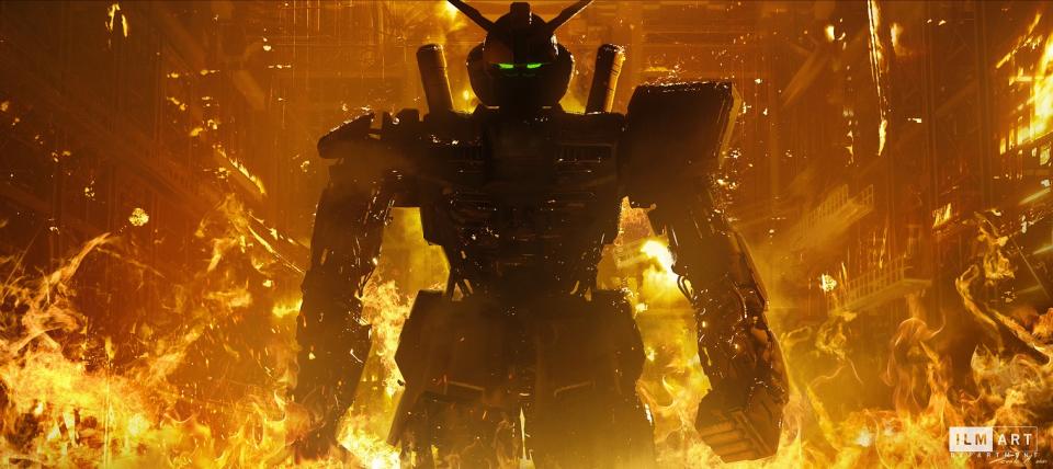 The background shows a warehouse or hangar on fire while the center depicts shadowy image of the main Gundam from concept art from Jordan Vogt-Roberts' upcoming Mobile Suit Gundam live-action film.