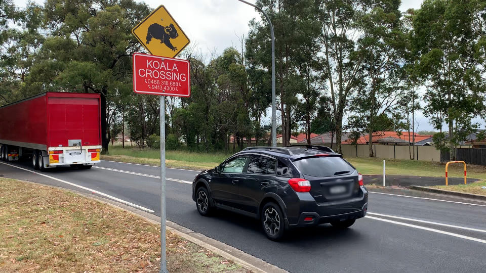 A car and truck pass a koala crossing sign on Appin Road in Campbelltown.