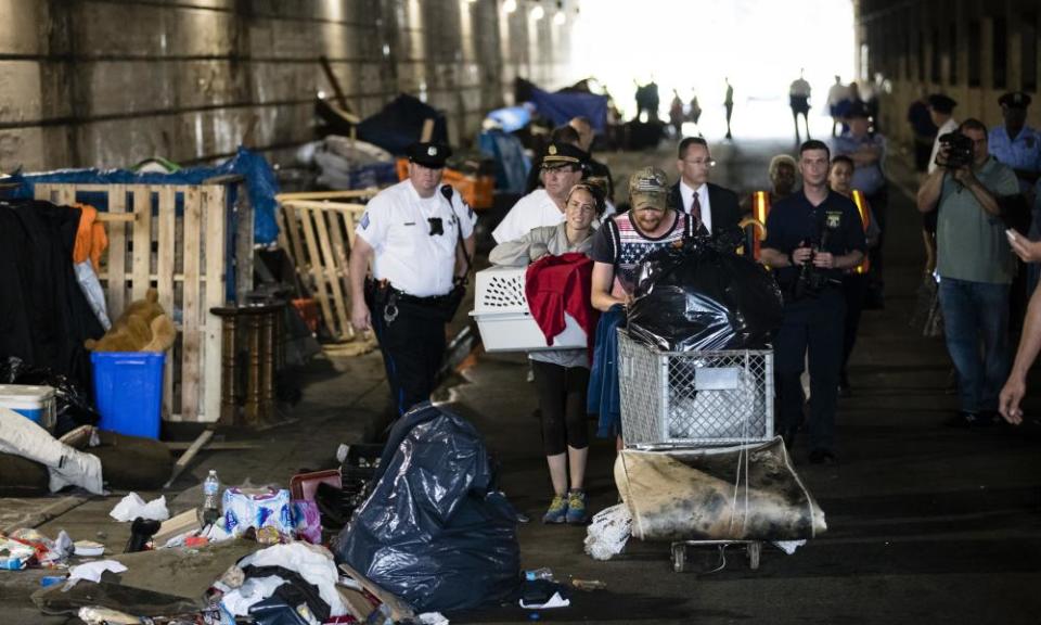 A couple carry their possessions out as police move in to clear an encampment in Philadelphia.