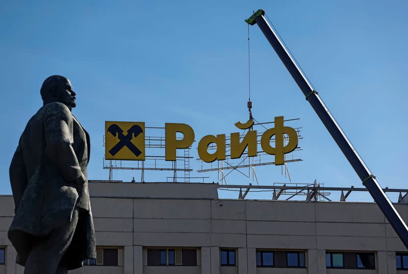 Workers remove a signboard advertising Raiffeisen Bank in Moscow
