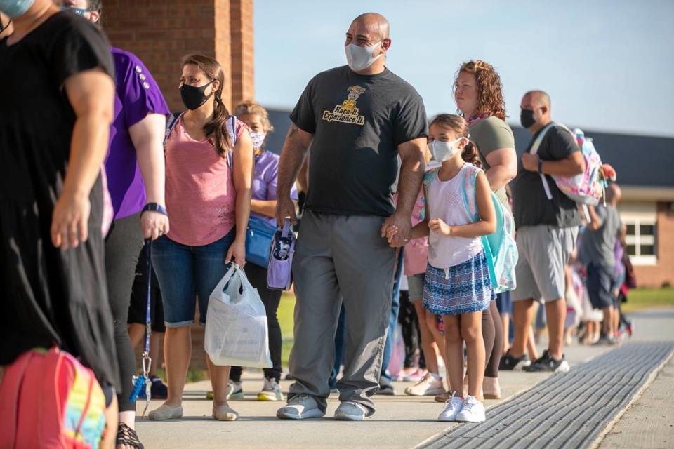 Fourth-grader Giuliana Melillo waits with her parents Jimmy and Jennifer Melillo to enter Thanksgiving Elementary School for the first day of classes on Monday, August 23, 2021 in Selma, N.C.