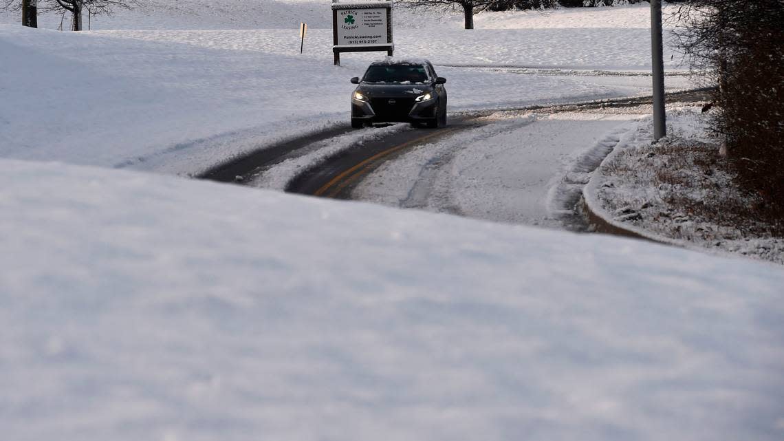 A car travels along a snow-covered street Thursday in Lenexa. Several inches of wet snow fell overnight greeting commuters with slick roads.