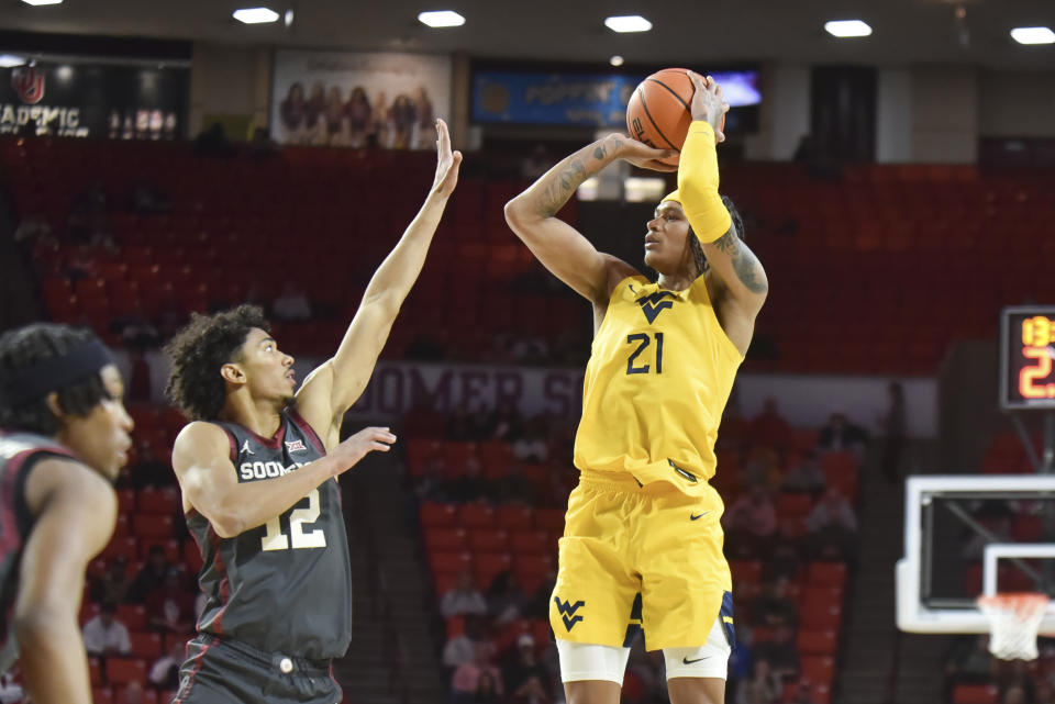 West Virginia guard RaeQuan Battle (21) shoots over Oklahoma guard Milos Uzan (12) during the second half of an NCAA college basketball game Wednesday, Jan. 17, 2024, in Norman, Okla. (AP Photo/Kyle Phillips)