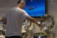 A hotel guests collects food from a breakfast buffet as a news broadcast report on the military exercises, in Pingtan in eastern China's Fujian province, Saturday, Aug. 6, 2022. China cut off contacts with the United States on vital issues Friday — including military matters and crucial climate cooperation — as concerns rose that the Communist government's hostile reaction to House Speaker Nancy Pelosi's Taiwan visit could signal a lasting, more aggressive approach toward its U.S. rival and the self-ruled island. (AP Photo/Ng Han Guan)