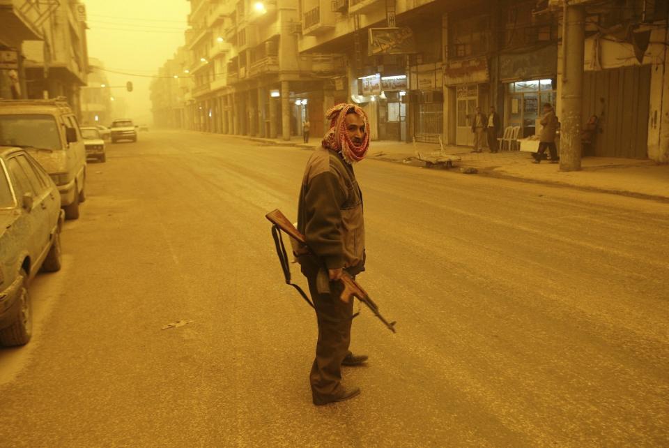 FILE - A militiaman patrols the streets of Baghdad, Iraq during a sandstorm March 26, 2003. (AP Photo/Jerome Delay, File)