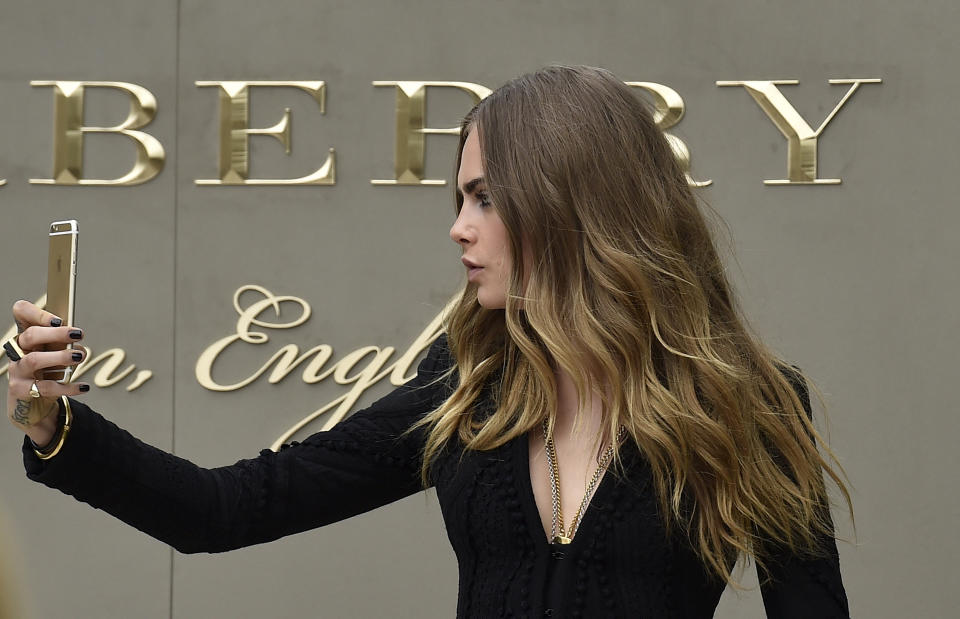 British model Cara Delevingne takes a selfie as she arrives for the Burberry Spring/Summer 2016 collection during London Fashion Week September 21, 2015. REUTERS/Toby Melville 