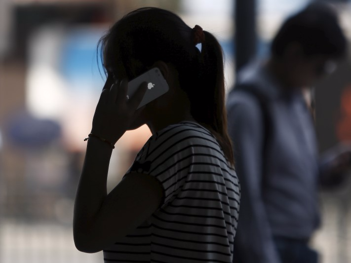 A woman speaks on her iPhone as she walks on a busy street in downtown Shanghai September 10, 2013. REUTERS/Aly Song/File Photo 