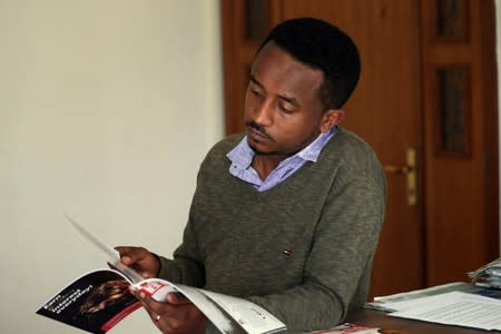 Eritrean refugee Berhane reads news magazine with cover photo of Ethiopian PM in Addis Ababa