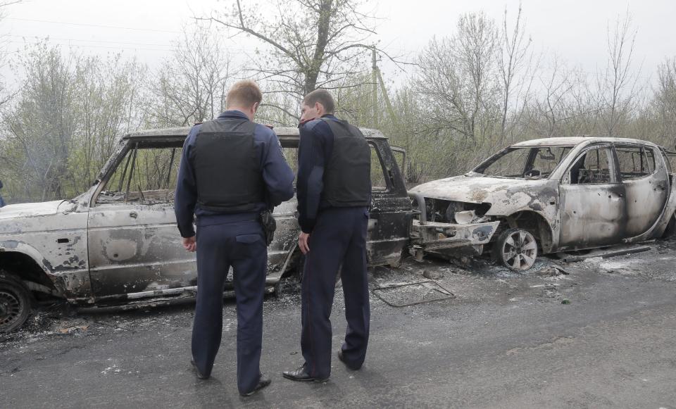 Local police officers inspect burnt-out cars after a night fight at the check point which is under the control of pro-Russian activists in the village of Bulbasika near Slovyansk, Ukraine, Sunday, April 20, 2014. At least one person was killed. Pro-Russian insurgents defiantly refused to surrender their weapons or give up government buildings in eastern Ukraine, despite a diplomatic accord reached in Geneva and overtures from the government in Kiev. (AP Photo/Efrem Lukatsky)