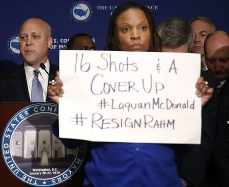 A protester against Chicago Mayor Rahm Emanuel (not pictured) stands in front of New Orleans Mayor Mitch Landrieu (L) at the opening press conference of the U.S. Conference of Mayors in Washington January 20, 2016. REUTERS/Gary Cameron