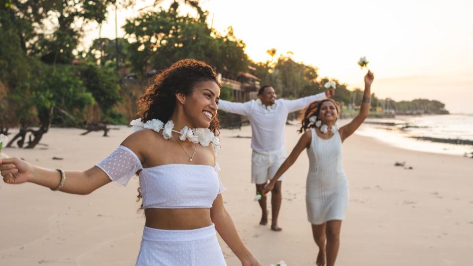 happy friends celebrating reveillon on the beach, running and holding white flowers paraiso beach, mosqueiro