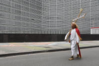 A protestor marches with a cross past EU headquarters during a demonstration against COVID-19 measures in Brussels, Sunday, Jan. 23, 2022. Demonstrators gathered in the Belgian capital to protest what they regard as overly extreme measures by the government to fight the COVID-19 pandemic, including a vaccine pass regulating access to certain places and activities and possible compulsory vaccines. (AP Photo/Geert Vanden Wijngaert)